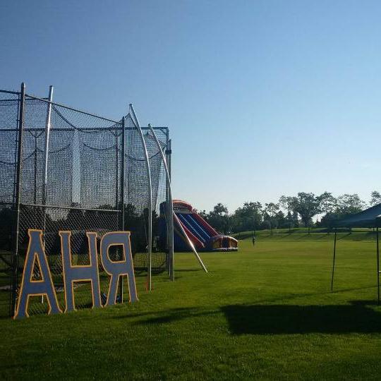 Blue RHA letters leaning agains a fence with an inflatable slide in the background